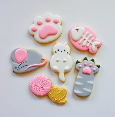 Colorful animal-themed cookies in various shapes, including a paw, fish, and mouse.