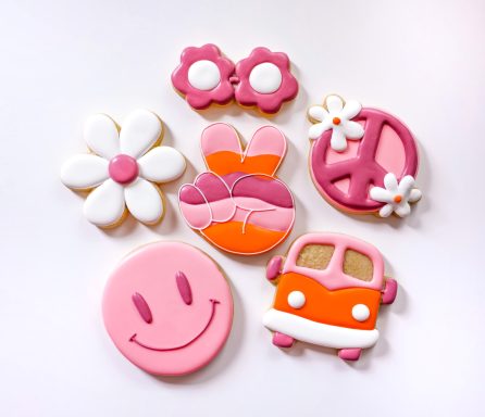 Colorful decorated cookies including flowers, peace signs, and a smiley face.