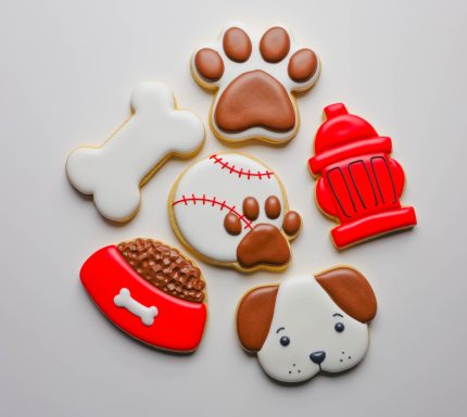 Colorful dog-themed cookies shaped like a bone, paw prints, fire hydrant, and dog bowl.