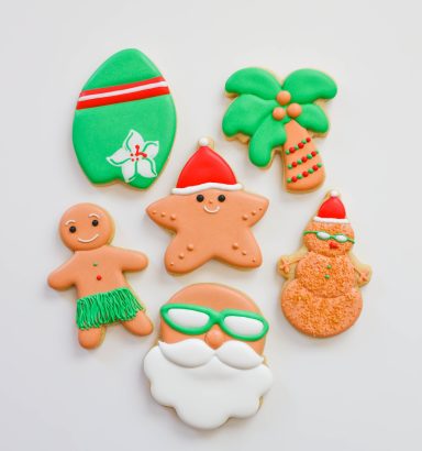 Decorative holiday cookies shaped like Santa, a gingerbread man, and a palm tree.